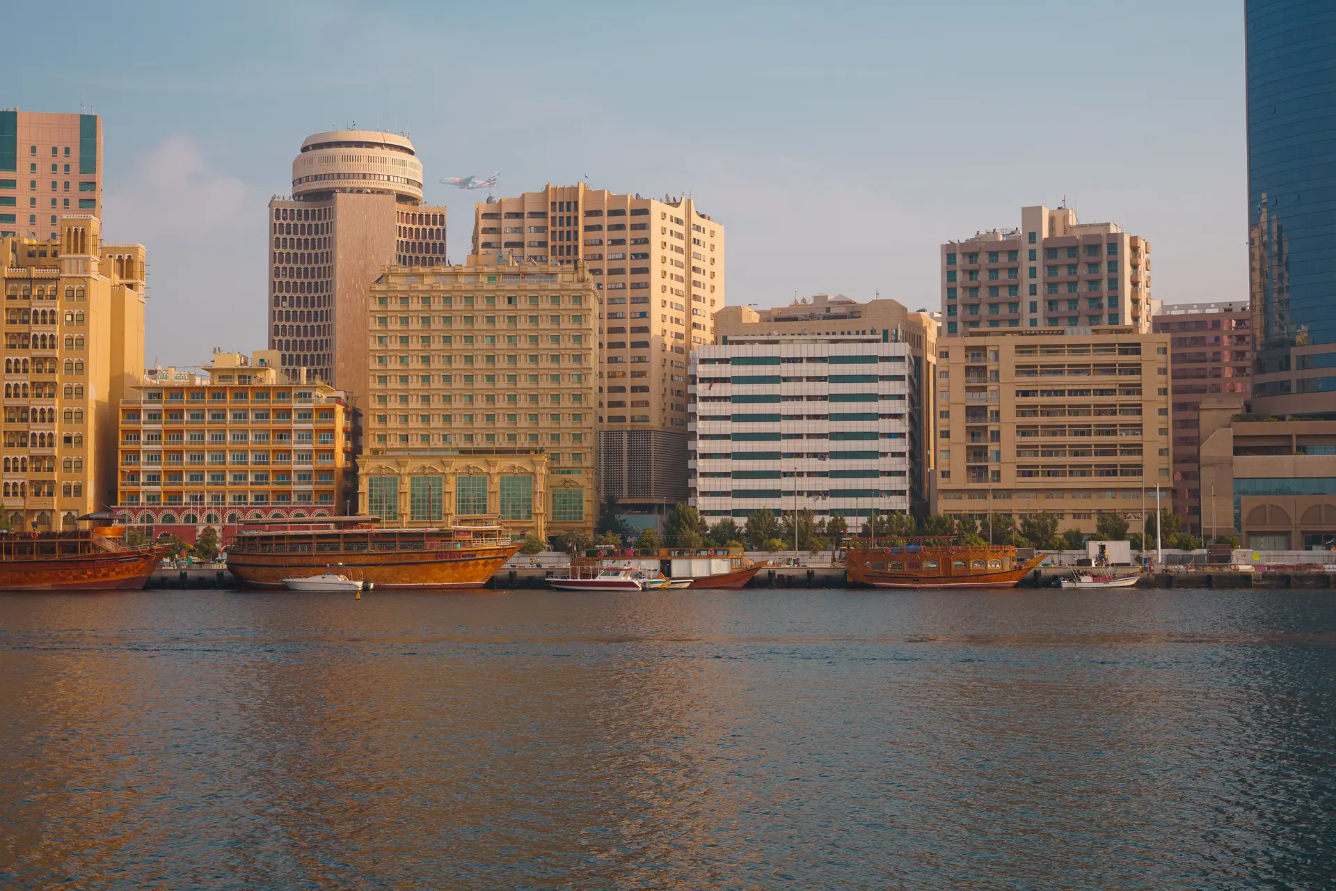 Dubai Creek at dusk, traditional wooden dhow boats moored in front of the modern skyline.