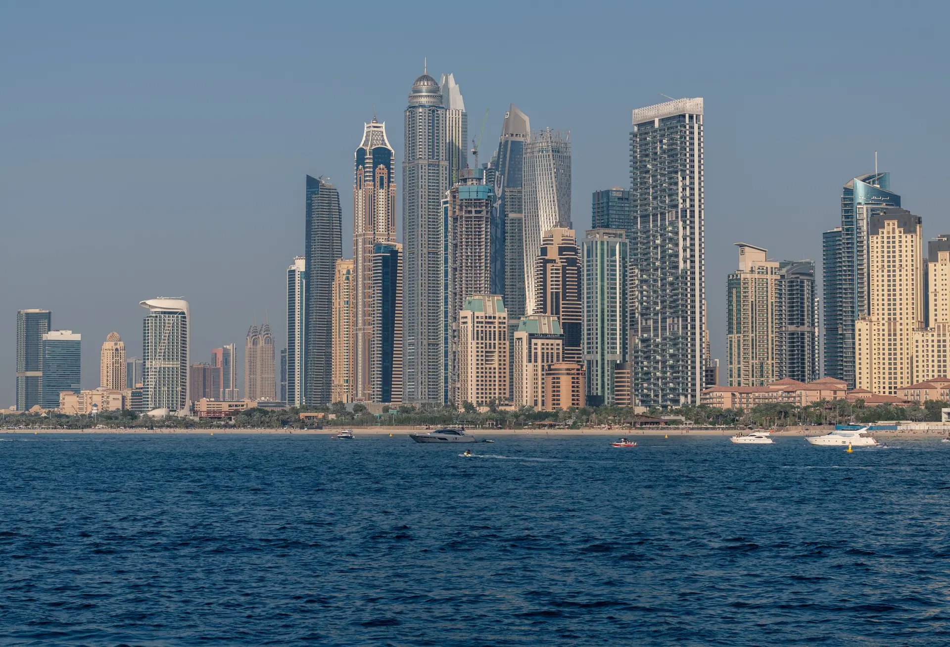 The towers of Dubai Marina seen across the water in daylight.